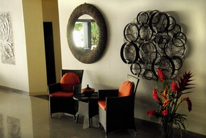 Un vestíbulo moderno con un espejo redondo, una obra de arte en la pared y una zona de estar con dos sillones y una mesa.