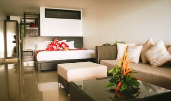 A modern hotel room with a large bed, a sofa, and a glass coffee table.