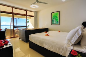 A hotel room with a bed, a chair, a table, and a view of the sea. - Garden Island Resort (Taveuni Island East)