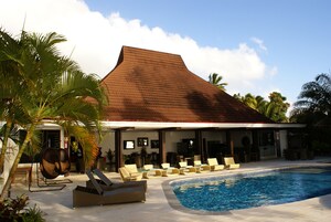 Un hotel con piscina, sillas de descanso y palmeras.