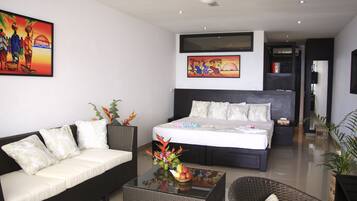 Een moderne hotelkamer met een groot bed, een slaapbank, een bijzettafeltje met een bloemdecoratie en twee schilderijen aan de muur.