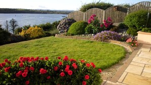 A landscaped garden with a lawn, a wooden fence, and a variety of flowering plants. - Channel View Bed & Breakfast (Baltimore)