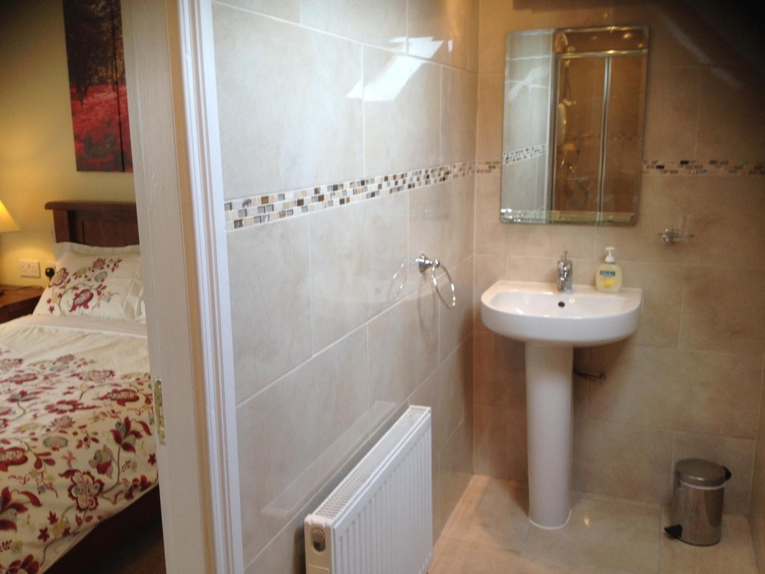 A bathroom with a white sink, a mirror, and a shower.