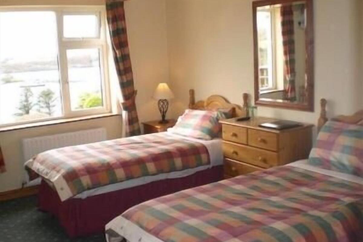 A bedroom with two beds, a dresser, a nightstand, a window with curtains, and a mirror on the wall.