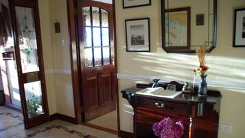 A hallway with a wooden door, a desk with a vase of flowers, and framed pictures on the wall.