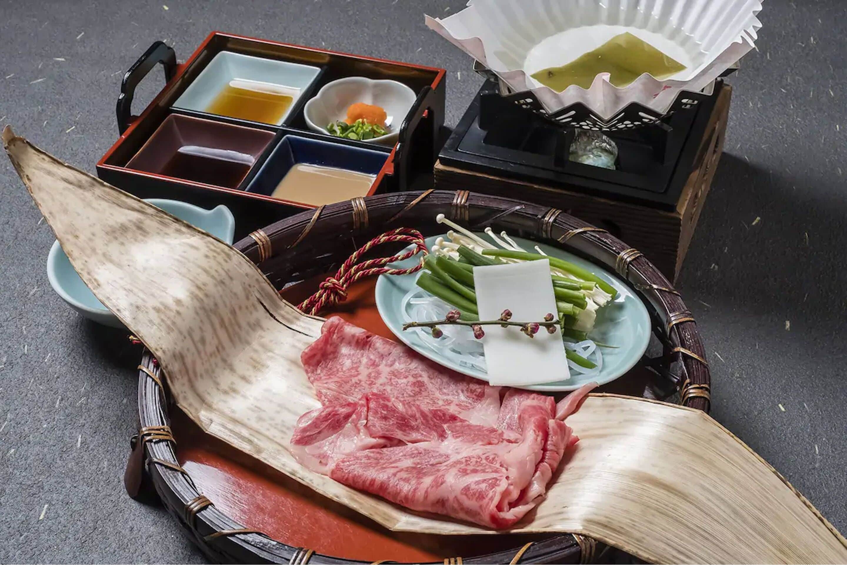A traditional Japanese meal setup with a woven tray, sashimi, and a box of condiments.