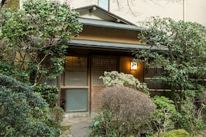 A traditional Japanese house with a wooden gate, a stone pathway, and lush greenery. - Yamagaso (Hakone)