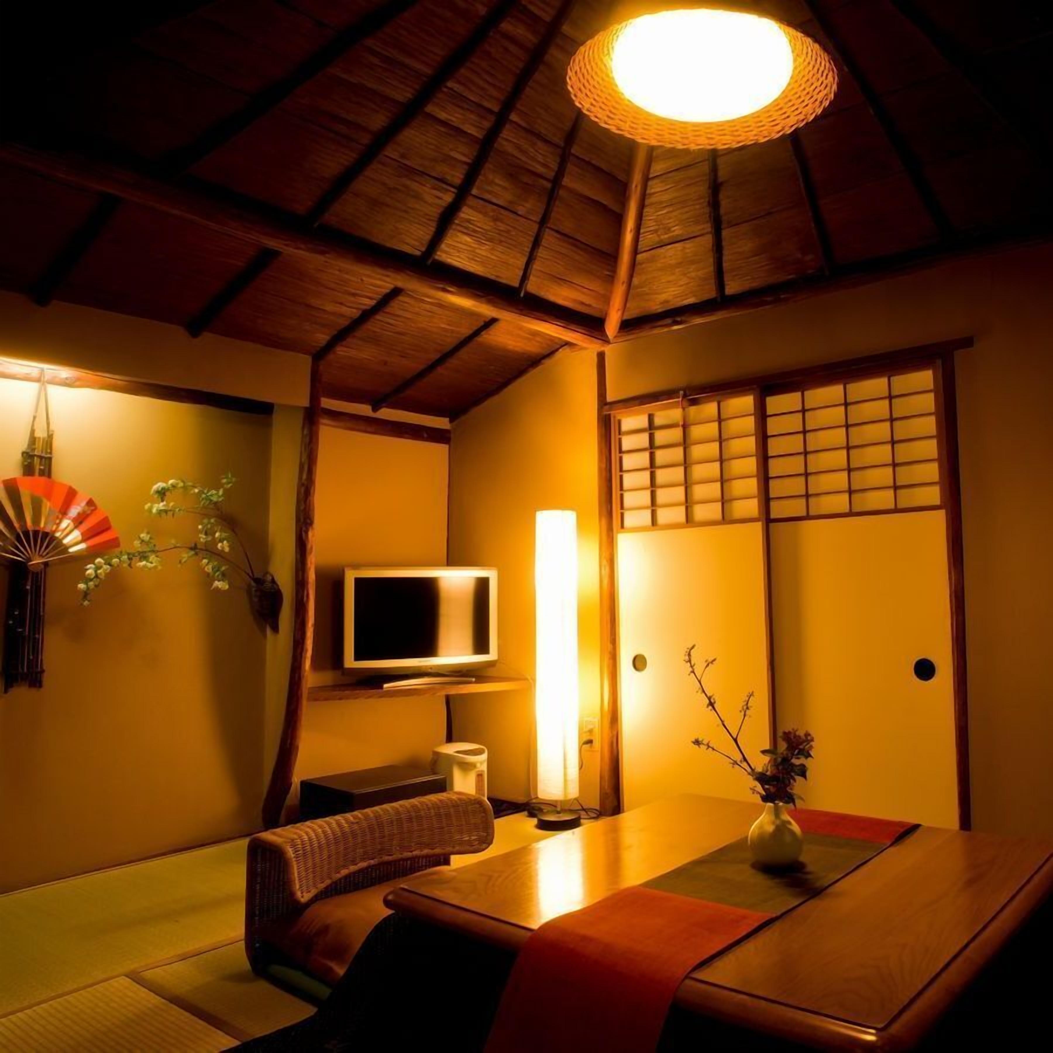 A traditional Japanese room with tatami flooring, a television, a fan, and a shoji screen door.