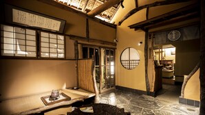 A traditional Japanese room with tatami flooring, a low table with a tea set, and sliding doors leading to another room.