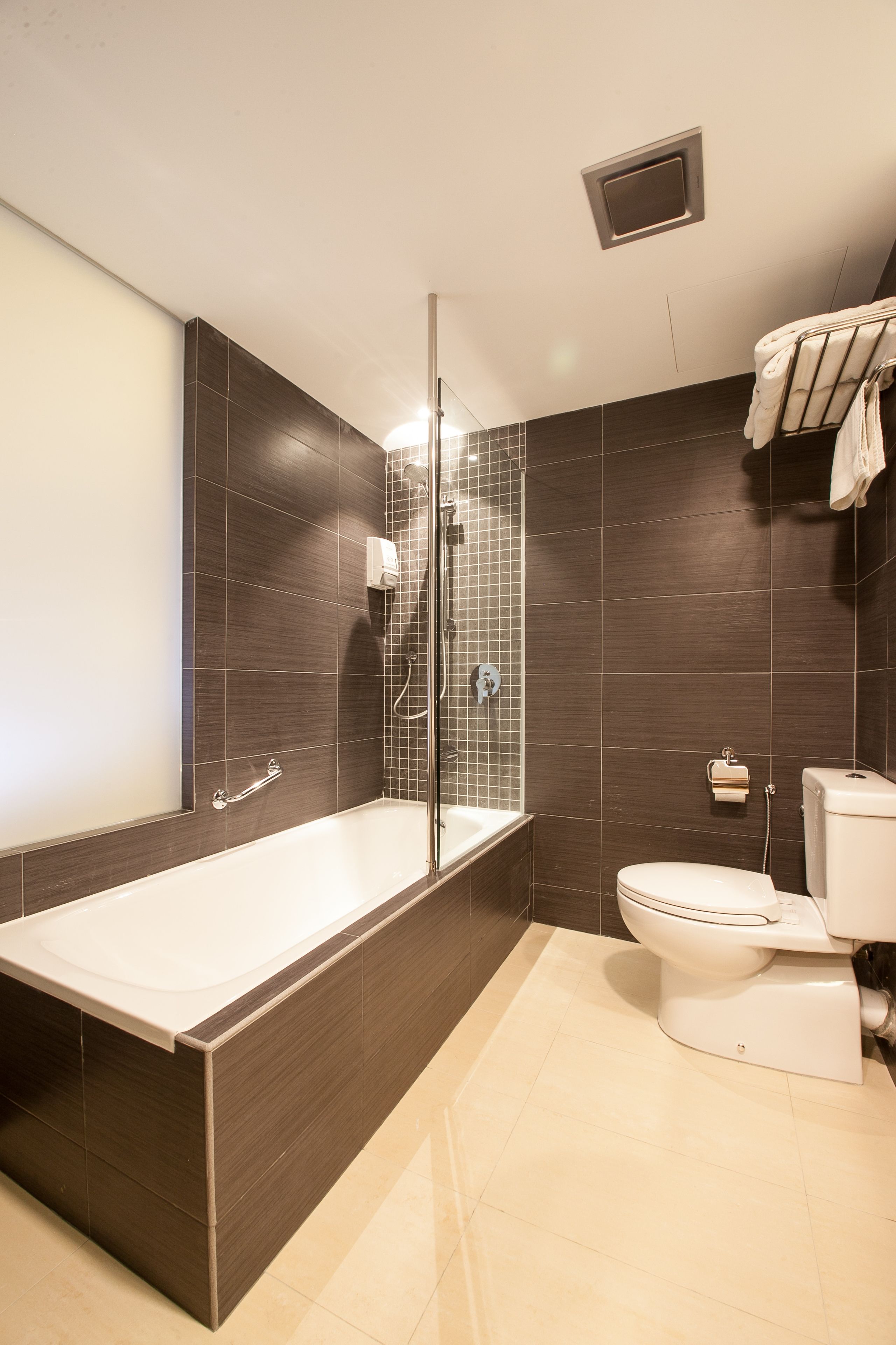 A modern bathroom with a bathtub, toilet, and shower.