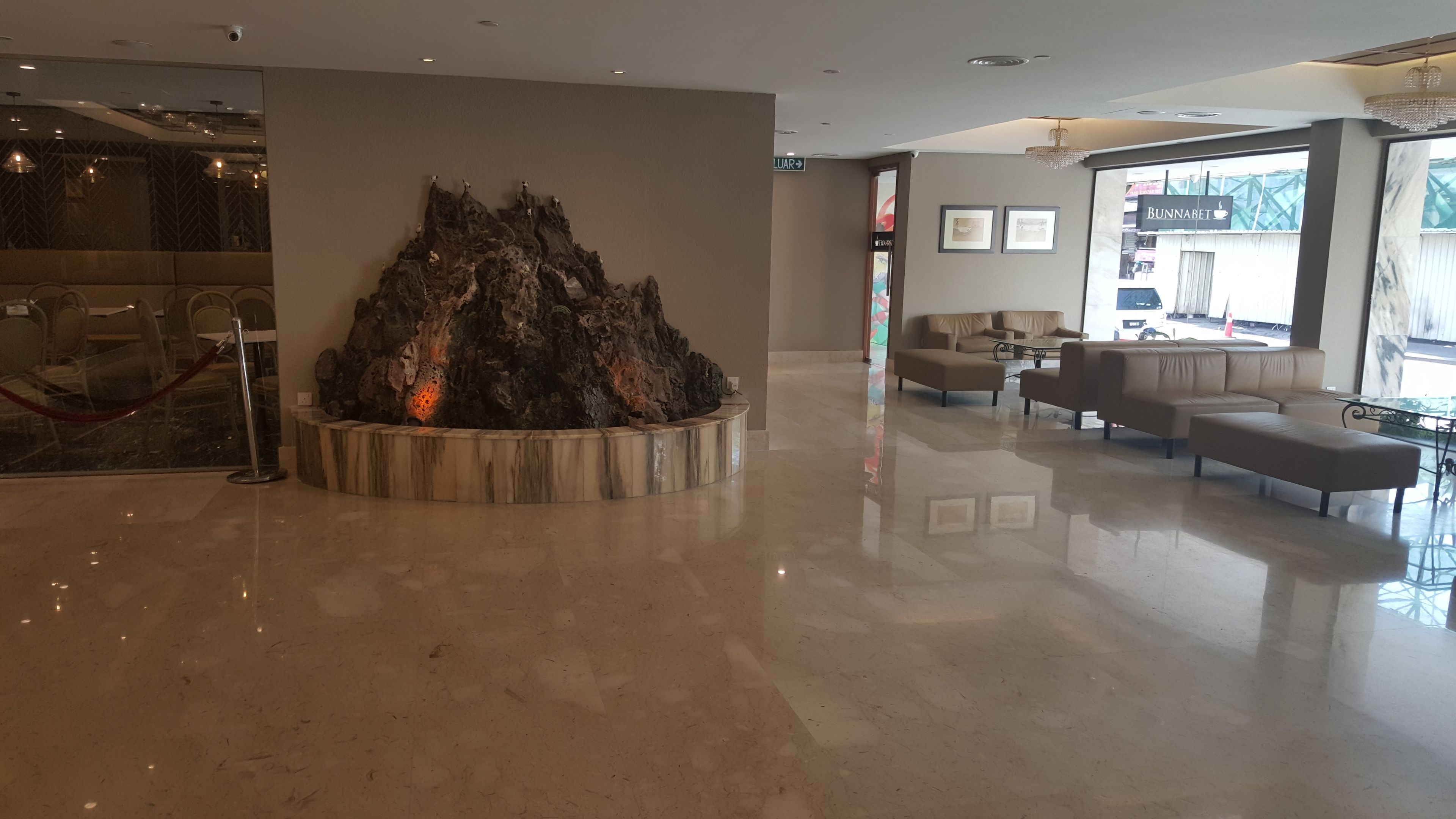 A lobby with a central rock feature, seating area, and a view of the outside.