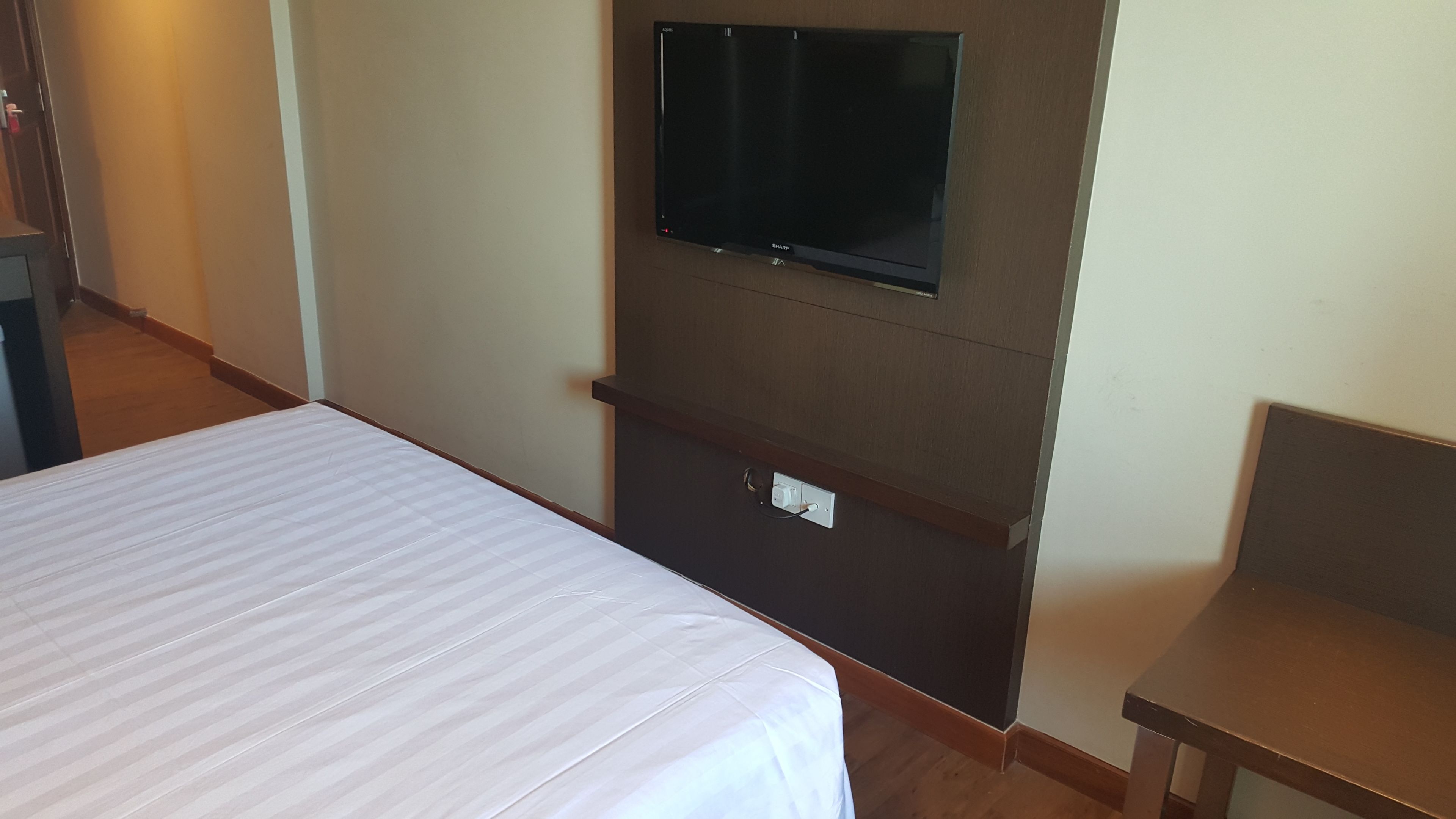 A hotel room with a bed, a television mounted on the wall, and a small table.