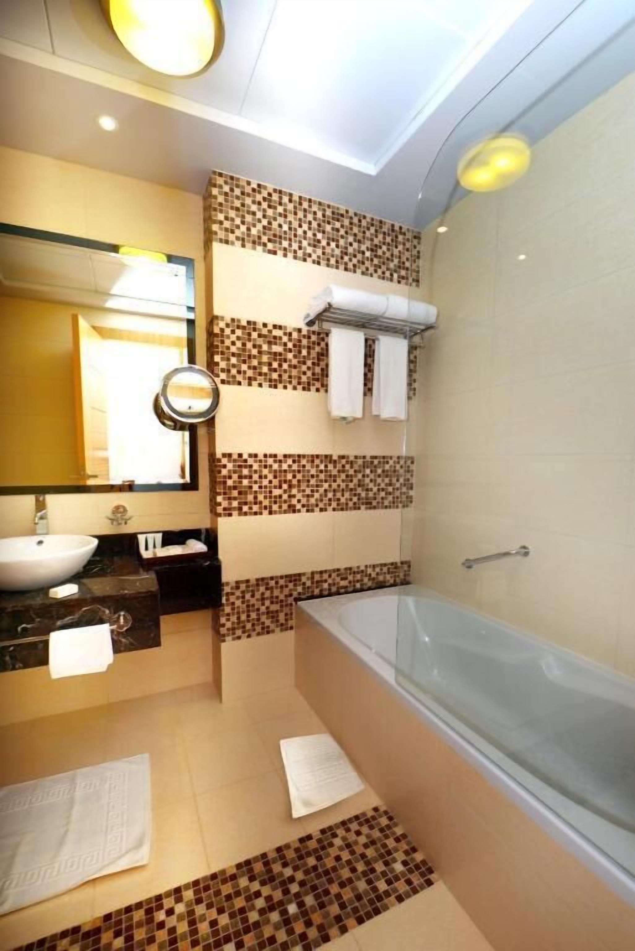 Une salle de bain moderne avec une grande baignoire, un lavabo et un miroir.