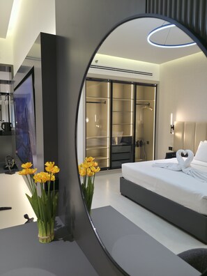A modern bedroom with a large bed, a walk-in closet, and a mirror reflecting the room. - Copthorne Hotel Sharjah (Sharjah)