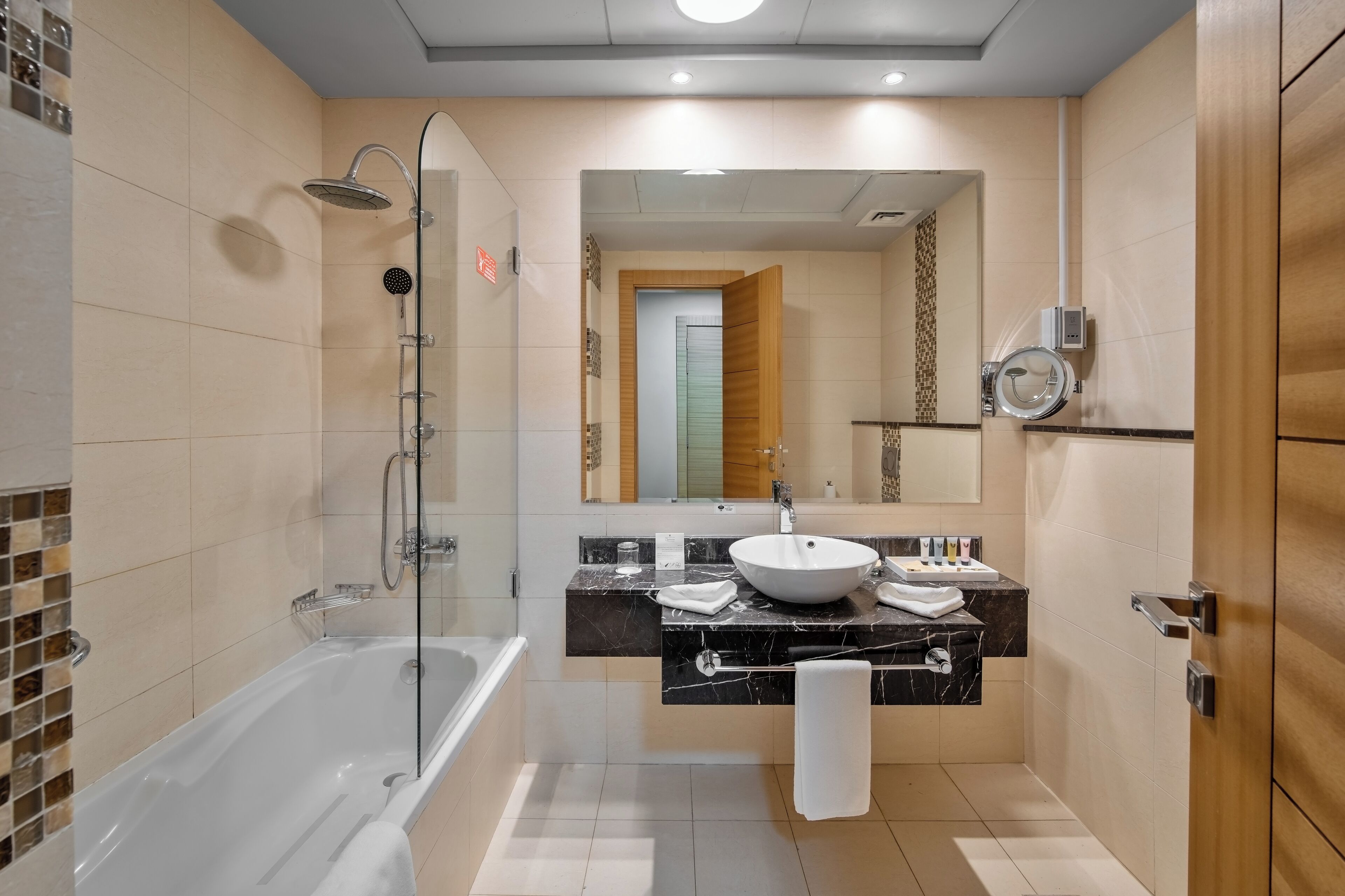A modern bathroom with a bathtub, a large mirror, a vanity with a sink, and a shower area.