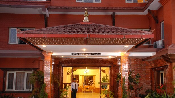 The entrance of Hotel Greenwich Village with a tiled roof, brick facade, and potted plants. - Hotel Greenwich Village (Lalitpur)