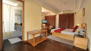 A hotel room with a bed, bedside table, nightstand, and a television. - Hotel Greenwich Village (Lalitpur)