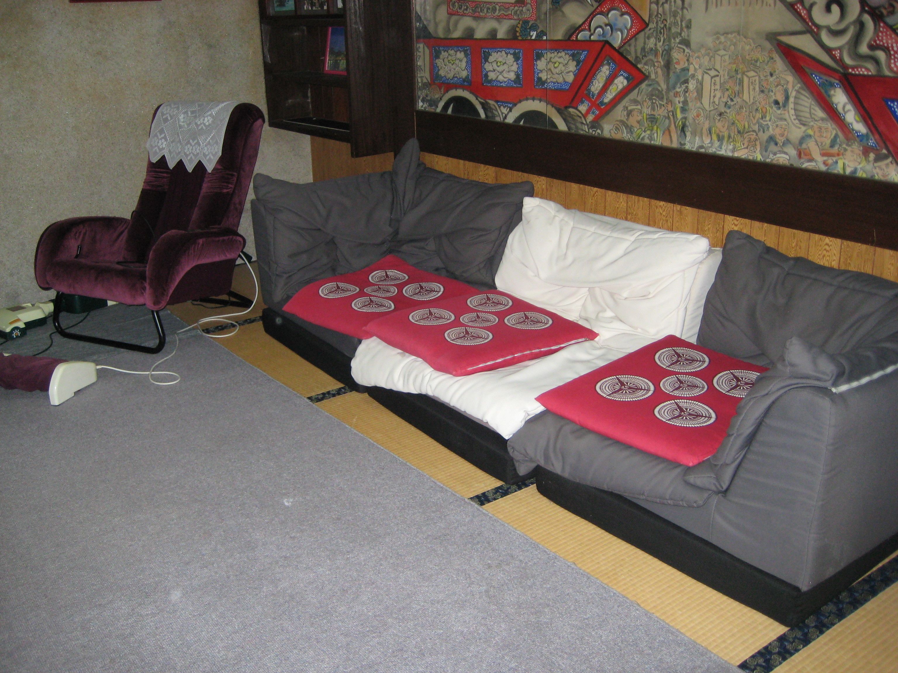 A living room with a grey sofa, a purple armchair, and a red patterned throw blanket.