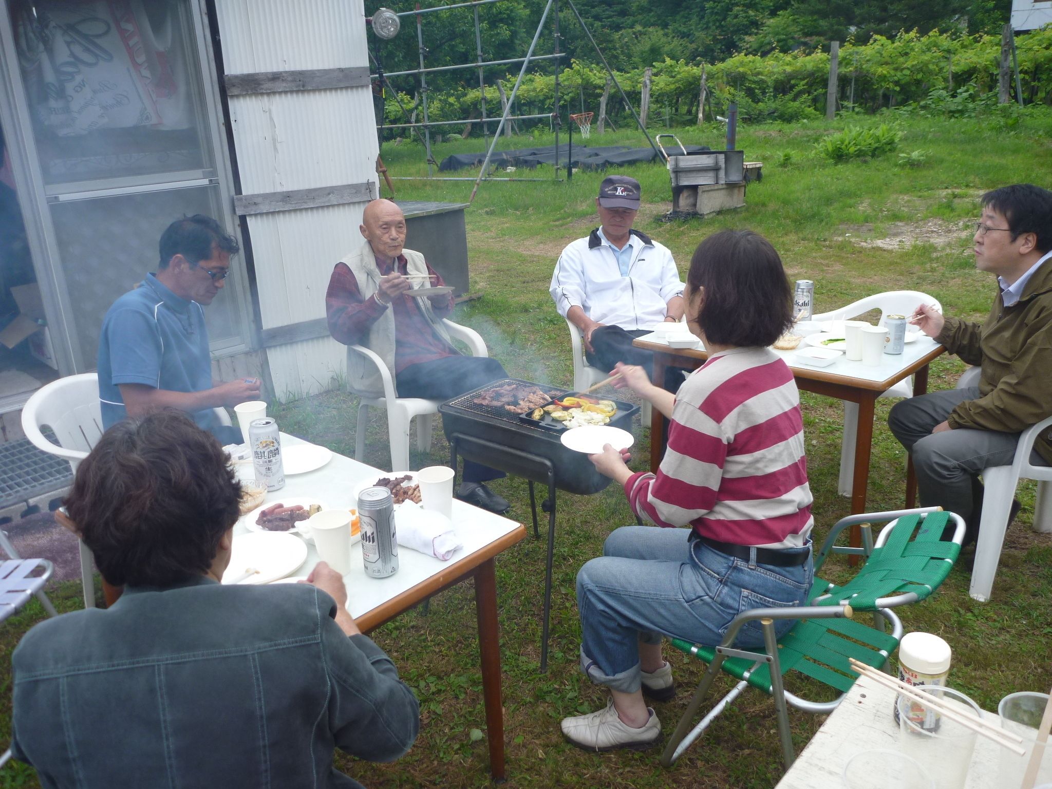 Un grupo de personas reunidas alrededor de una parrilla al aire libre.