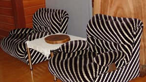 A room with two striped armchairs and a small wooden table with a white lace tablecloth. - Towadako Backpackers (Towada)