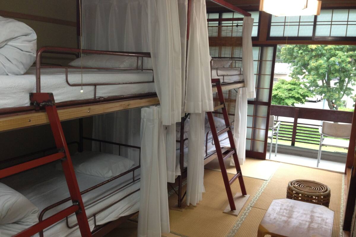 Un dormitorio con literas, suelo de tatami y vistas al exterior.