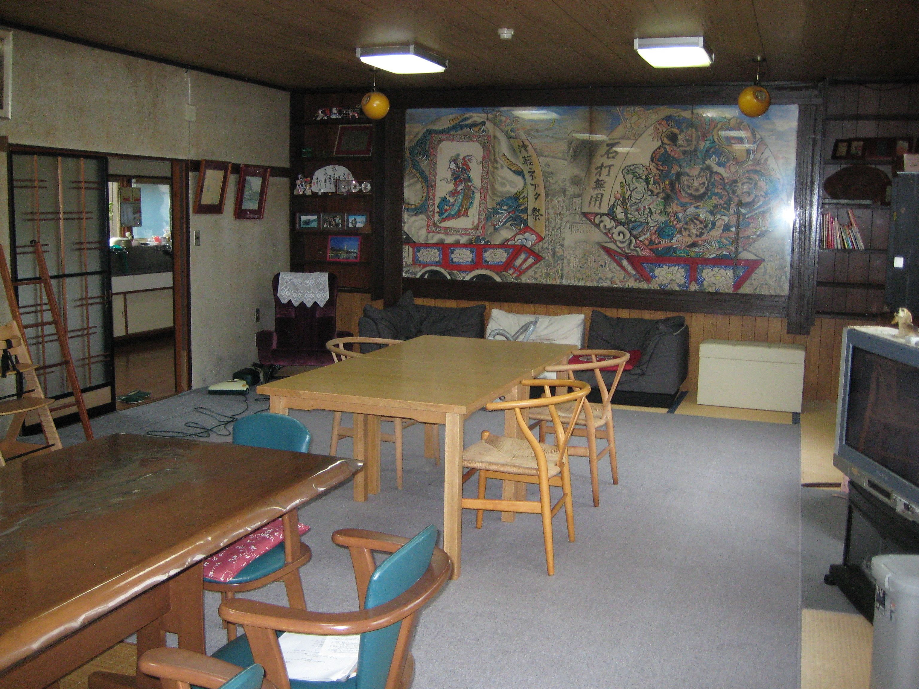 A traditional Japanese-style room with tatami mat flooring, a low wooden table, and a television.