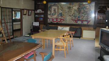 A traditional Japanese-style room with tatami mat flooring, a low wooden table, and a television.