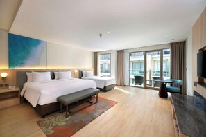 A hotel room with a large bed, a smaller bed, a bench, a desk, and a television. - Harper Kuta by ASTON (Legian)
