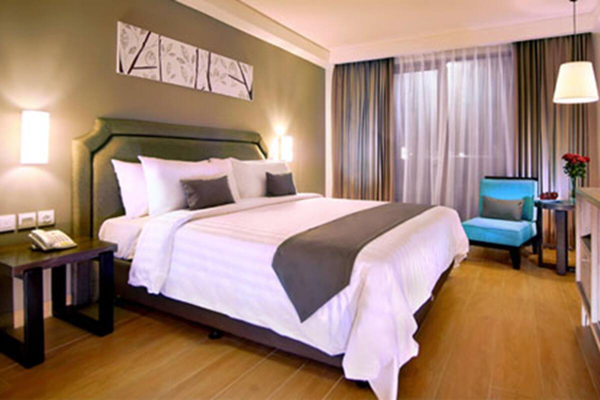 A hotel room with a large bed, a desk with a telephone, a television, and a chair.
