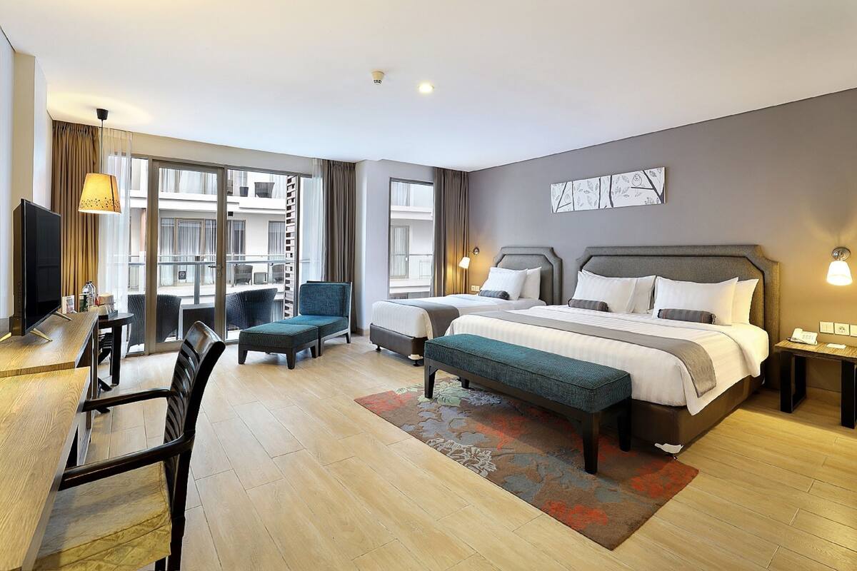 A hotel room with a large bed, a desk, a chair, and a balcony with a view.