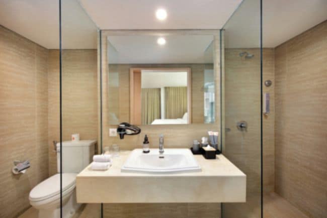 Un baño moderno con ducha envuelta en vidrio, un lavabo blanco y un espejo sobre él.