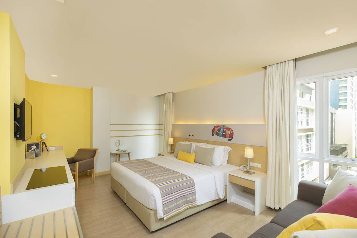 Una habitación de hotel con cama, mesitas de noche, escritorio y una silla.