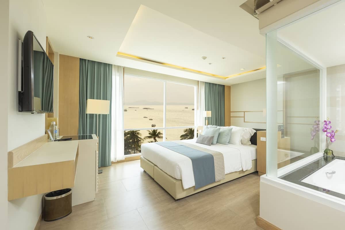 Una habitación de hotel moderna con balcón, una cama, un escritorio y un baño con bañera.