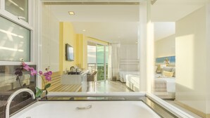 A modern bathroom with a large bathtub, a sink, and a mirror. There is a window with a view of the room. - Pattaya Sea View Hotel (Pattaya)