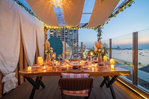 A table set for dining with candles, a view of the beach, and a cityscape in the background. - Pattaya Sea View Hotel (Pattaya)
