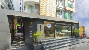 A modern hotel with a glass facade, outdoor seating, and a staircase leading to the entrance. - Pattaya Sea View Hotel (Pattaya)