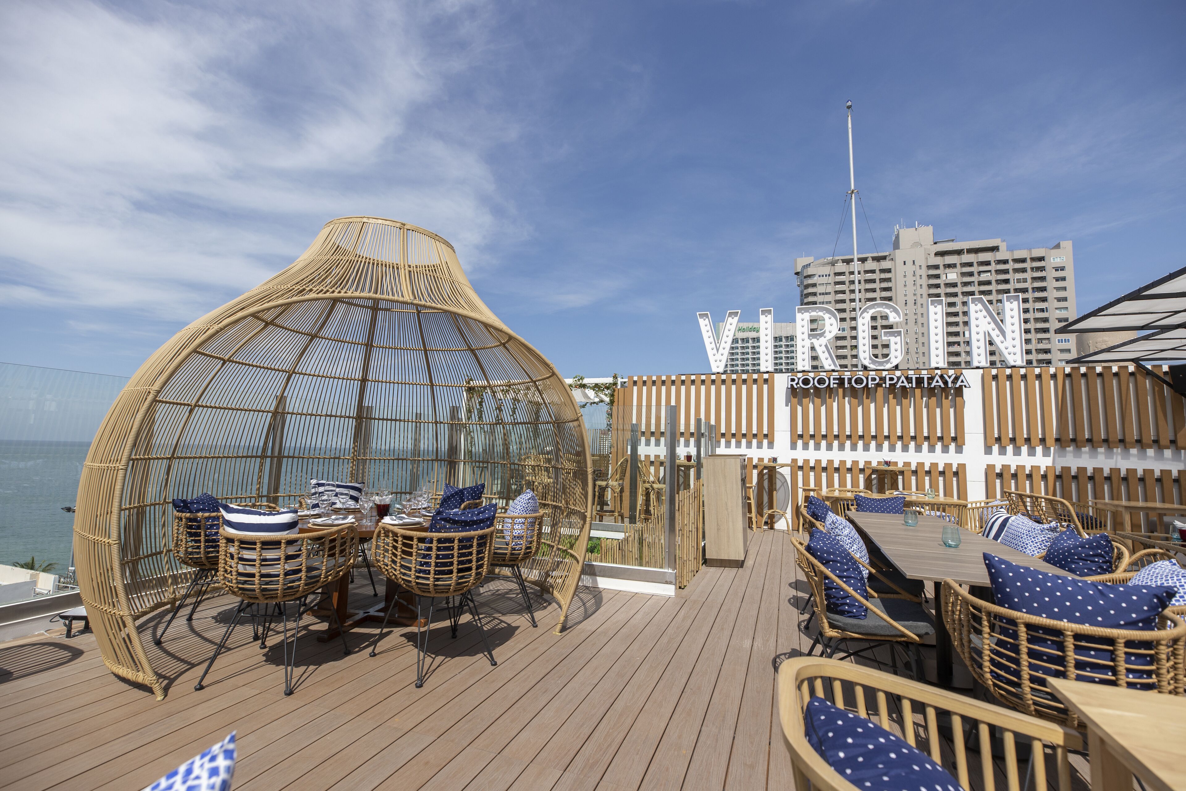A deck with wicker furniture and a glass dome structure, overlooking the sea.