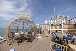 A deck with wicker furniture and a glass dome structure, overlooking the sea. - Pattaya Sea View Hotel (Pattaya)