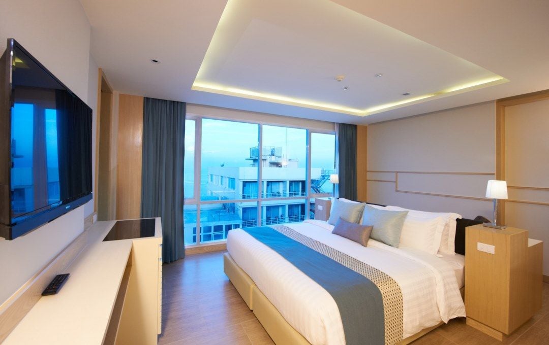 Una habitación de hotel moderna con una cama grande, un escritorio y vistas a la ciudad.