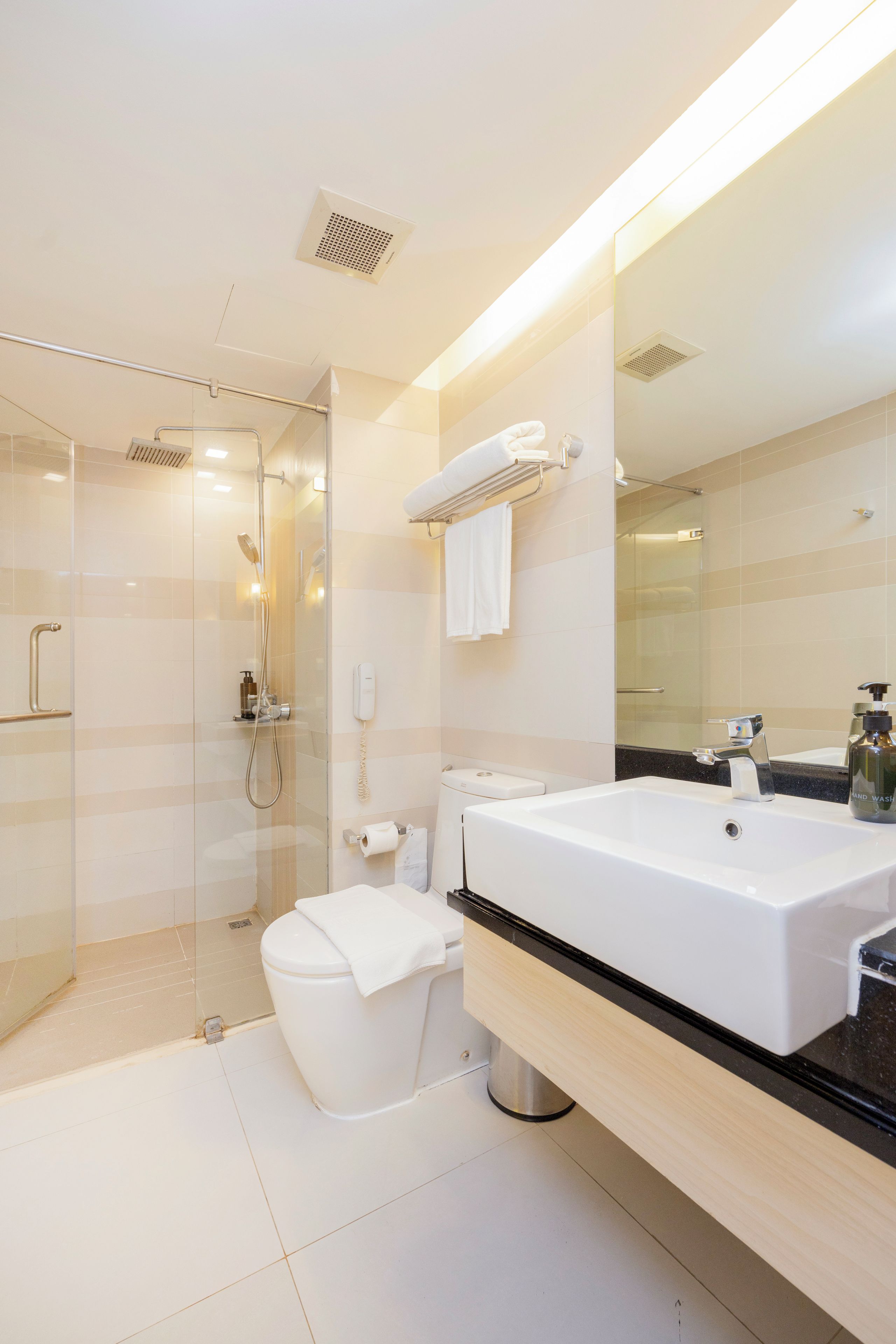 Un baño moderno con ducha envuelta en vidrio, un lavamanos grande de color blanco y un espejo sobre el mueble.