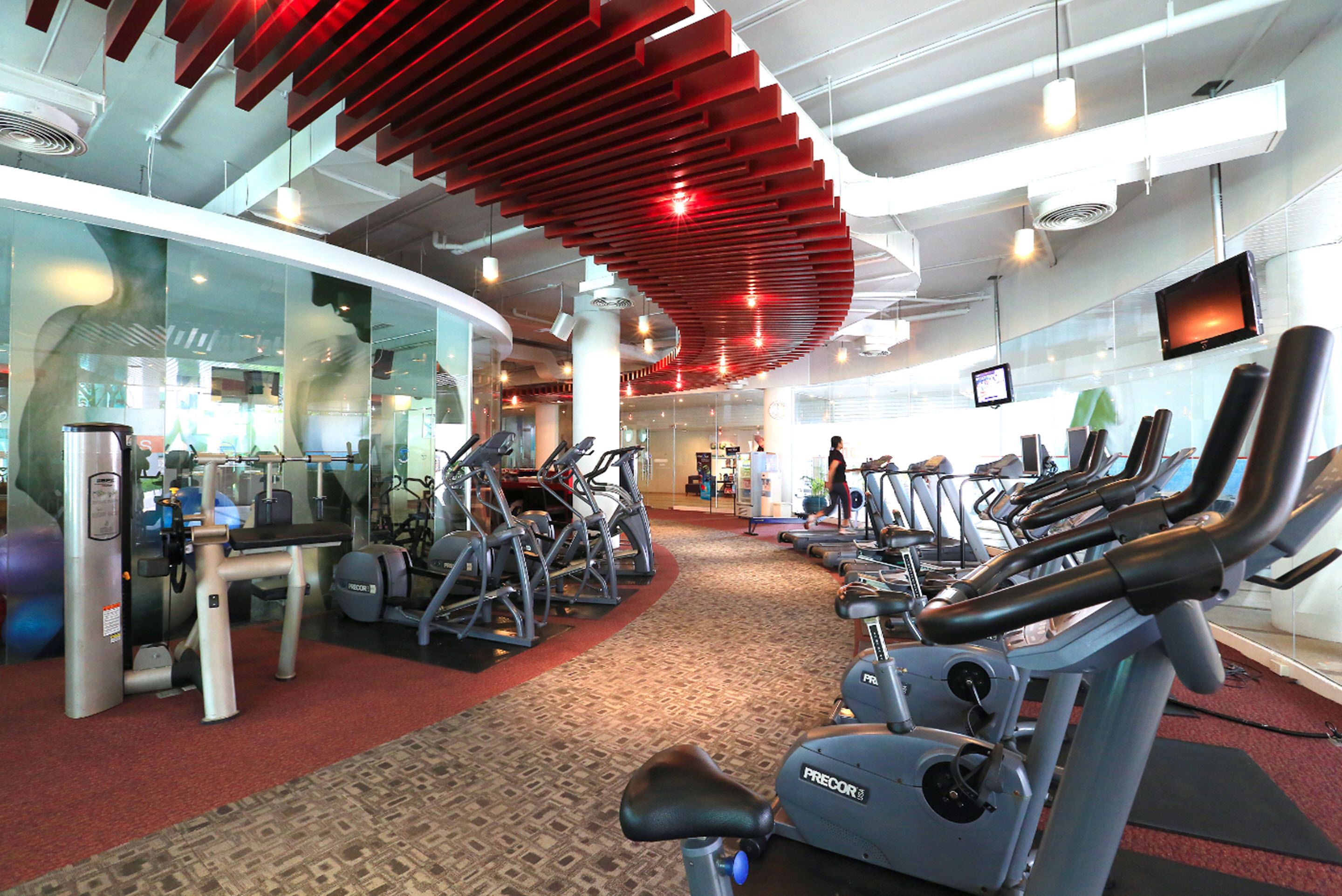 Academia com máquinas de cardio, equipamentos de musculação e um design de teto curvo.