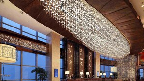 Un hall d’entrée spacieux avec un plafond haut, un comptoir de réception et un grand lustre.