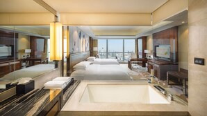 Une chambre d’hôtel avec un grand lit, une salle de bain séparée avec une baignoire, un bureau et une télévision.