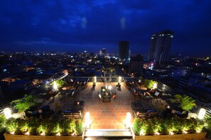 A rooftop terrace with outdoor seating, potted plants, and city lights in the background. - Kolab Sor Phnom Penh Hotel (Phnom Penh)