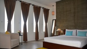 A bedroom with a large bed, a sofa, and a small table with a vase.
