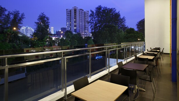 A restaurant with outdoor seating overlooking a cityscape at dusk. - Amaris Hotel Dr. Susilo Grogol (Jakarta)