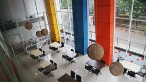 A modern interior with multiple tables and chairs, large windows, and colorful walls. - Amaris Hotel Dr. Susilo Grogol (Jakarta)