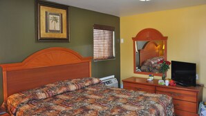 A bedroom with a wooden bed, a dresser, a television, and a framed picture on the wall. - Atlantic Economy Inn (Daytona Beach)