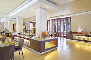 Un hall d’hôtel spacieux avec un buffet central, des espaces aménagés pour s’asseoir et une vue sur l’extérieur grâce à de grandes fenêtres.