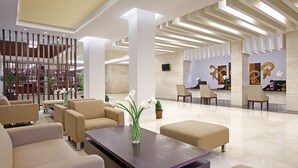 A modern lobby with sofas, a coffee table, and a reception desk. - Hotel Surya Yudha Purwokerto (Purwokerto)